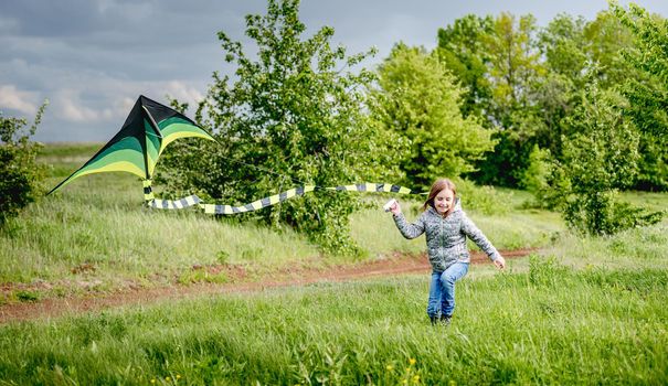Happy little girl flying bright kite