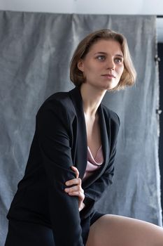 portrait of young caucasian woman with short hair posing in black suit jacket