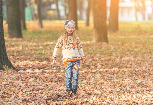 Girl walking across carpet of leaves