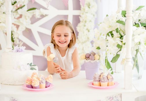 Little girl holding colorful sweet lollipops in the candy bar