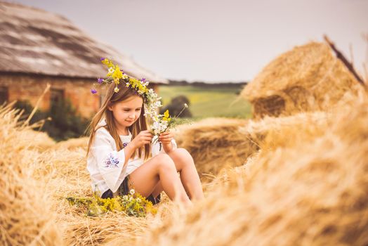 Little girl making floral band on haystack