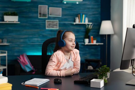 Little schoolkid wearing headset having online literature lesson on computer