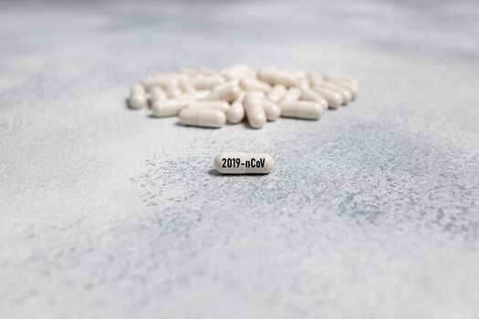 capsule of cure with sign 2019-nCoV on background of bunch of pills unfocused