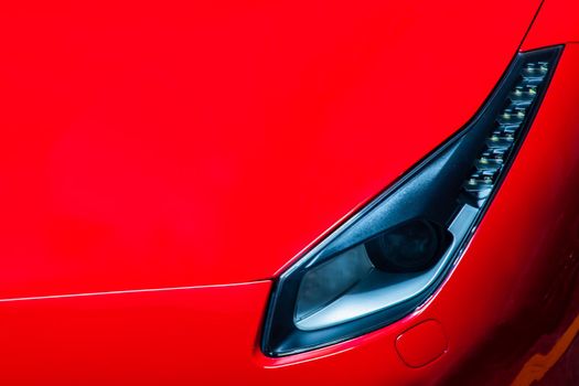 Close-up of Headlights of Red Ferrari car. 
