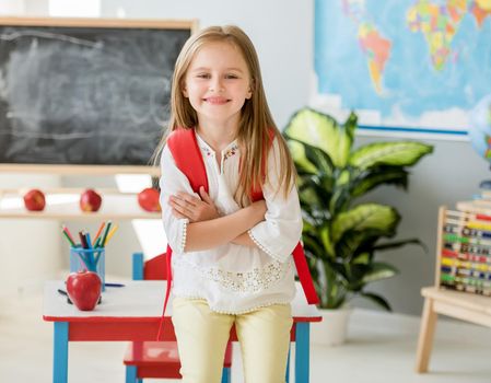 Little smiling blond girl standing in the school class