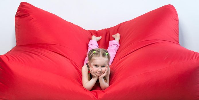 preschool girl lying on big red sofa