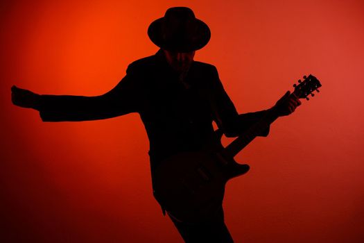 silhouette of guitarist on a red background.