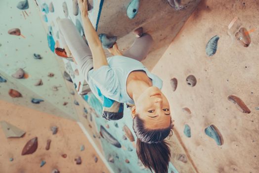 Smiling young woman climbing indoor