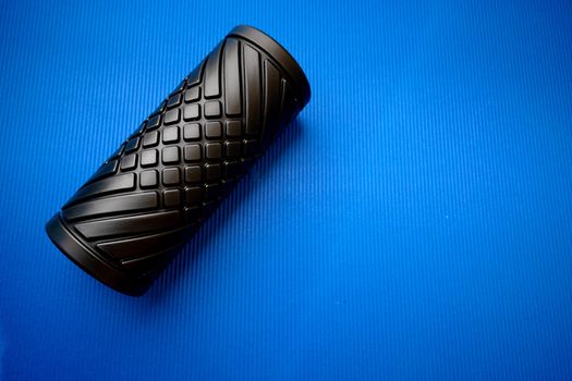 Sport fitness foam roller on blue mat, close up