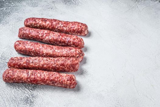 Fresh raw beef meat kebabs sausages. White background. Top view. Copy space