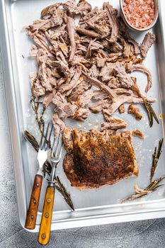 Texas bbq smoked puilled pork meat in a steel baking tray. White background. Top view