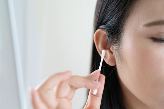woman cleaning ear with cotton swab. Healthcare and ear cleaning concept