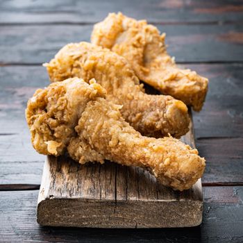 Crispy fried chicken leg on old dark wooden table