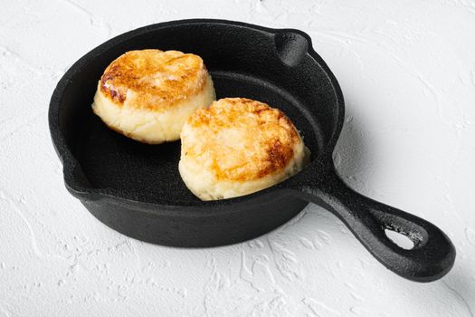Cheese cakes Sweet pancakes on cast iron frying pan skillet on cast iron frying pan skillet, on white stone table background