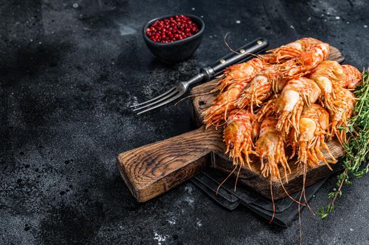 Cooked Greenland Prawn Shrimp on a wooden board. Black background. Top view. Copy space