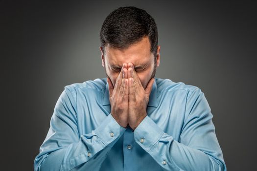 Portrait of upset man covering his face by hands