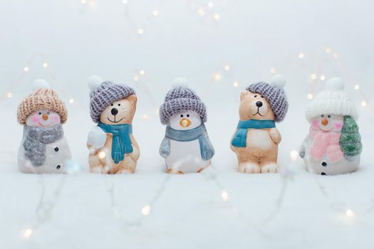 Decorative Christmas-themed figurines. The statuette of a cat, a penguin, a bear and two snowmen in a knitted hat on the white background.