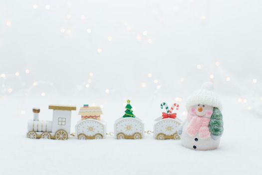Toy snowman near the wooden white christmas train on the white background