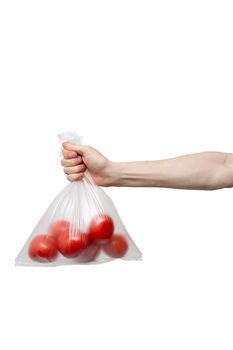 polythene bag held in hand isolated on white. man holding packet of red tomatoes