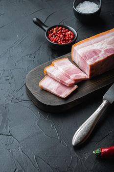 Smoked bacon, whole slab with herbs on black background with space for text
