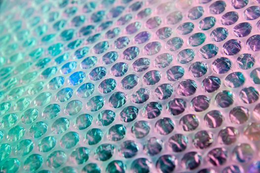 Holographic background in the style of the 80-90s. Real texture of bubble wrap film in bright acid colors.