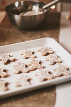 Christmas baking and cooking recipe concept. Food ingredients and preparation process of traditional homemade gingerbread men biscuits in the kitchen at home during winter holidays