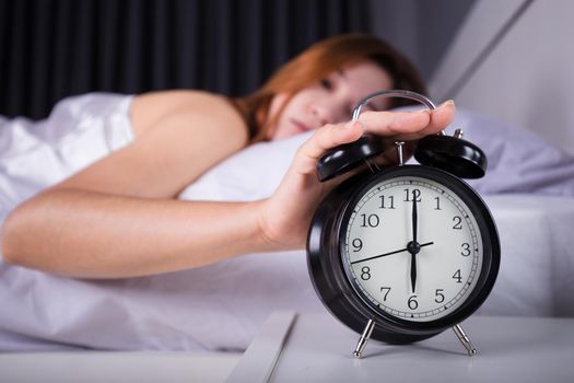 woman sleeping and wake up to turn off the alarm clock in morning