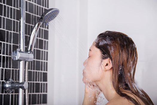 Woman is washing her face by shower 