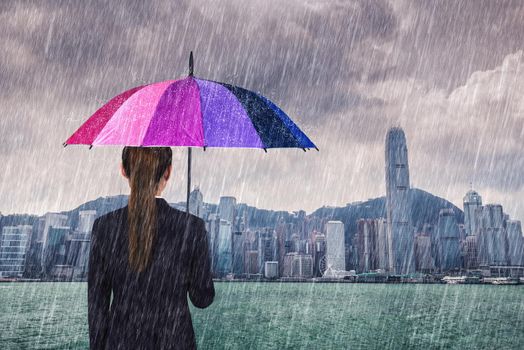 business woman holding umbrella with falling rain at victoria harbour, Hong Kong