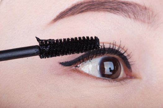 woman applying mascara on her eyelashes