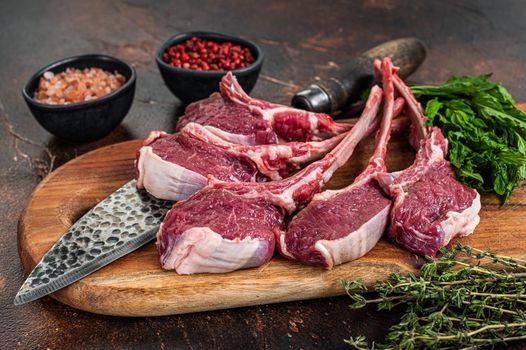 Raw lamb, mutton chops steaks on a wooden board. Dark background. Top view