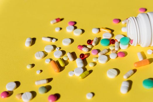 Pills isolated on yellow background.tablets and capsules.Healthcare and medical drugs concept with a closeup on pills spilling from a prescription pill bottle.Top view.