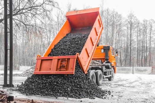 Dump truck in the industrial zone unloads coking coal from the body