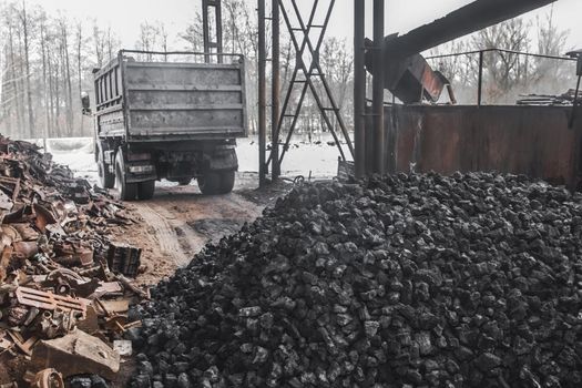 A dump truck at a landfill or on an industrial site unloaded a pile of coking coal from the body