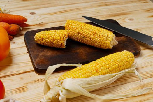 Cobs of corn on wooden cutting board