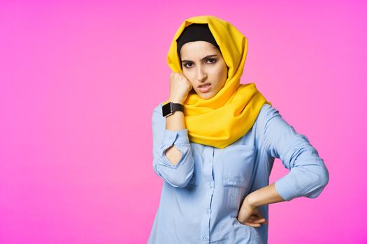 cheerful woman in yellow hijab electronic watch technology user pink background