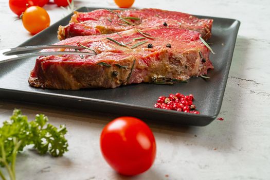 Marinated raw steaks on stone table with spices