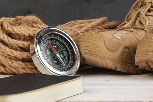 Compass surrounded by mountain gear tools on wooden background
