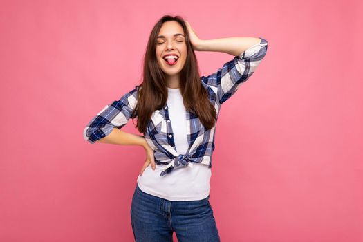 Photo shot of cute nice charming gorgeous attractive pretty youngster happy woman wearing stylish clothes isolated over colorful background with copy space and showing tongue