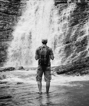 Explorer man looking at waterfall