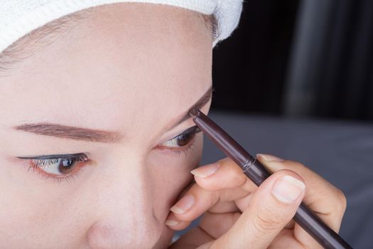 woman using pencil makeup eyebrow 