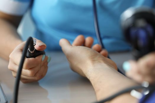 Cardiologist measuring blood pressure to patient in clinic closeup