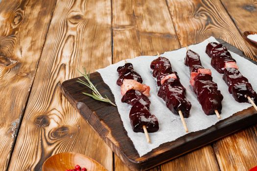 Raw liver kebab on skewers on wooden board