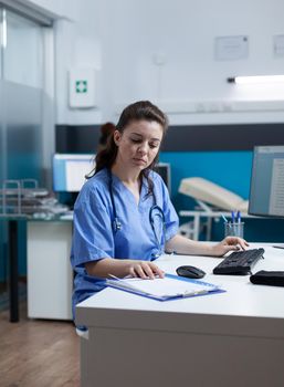 Practitioner nurse with stethoscope analyzing healthcare treatment on medical paperwork typing sickness expertise working in hospital examination office. Woman asisstance checking disease results