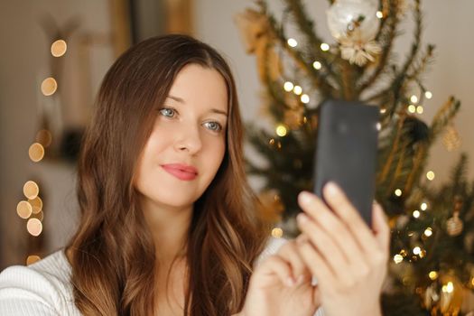 Christmas phone call and holiday greeting concept. Happy smiling woman using mobile smartphone on xmas day