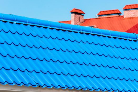 Blue tiles of the roof of a house or building against the cloud sky, close up