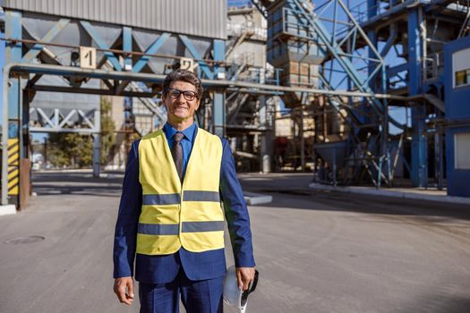 Cheerful male engineer standing outdoors at factory