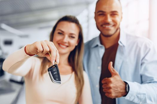 Happy excited couple buying a new car and showing keys