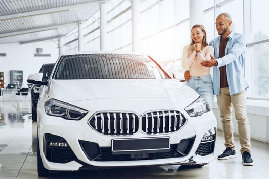 Young happy couple choosing a car in car dealership