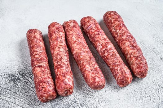 Fresh raw beef meat kebabs sausages. White background. Top view